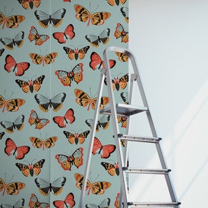 May include: A roll of wallpaper with a repeating pattern of colorful butterflies on a light blue background. A silver step ladder is in the foreground.