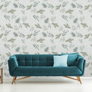 Puede incluir: Un sofá azul turquesa con patas de madera delante de una pared con fondo gris claro y un patrón repetitivo de hojas verdes y blancas.