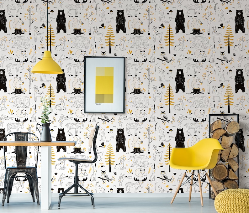 May include: White wallpaper with a repeating pattern of black bears, deer, squirrels, and other woodland creatures. The wallpaper is accented with yellow trees and leaves. The wallpaper is shown in a room with a yellow chair, a table, and a picture frame.