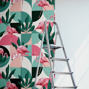 May include: Pink flamingos and tropical leaves on a geometric pattern wallpaper. The wallpaper is being installed on a white wall with a silver step ladder.