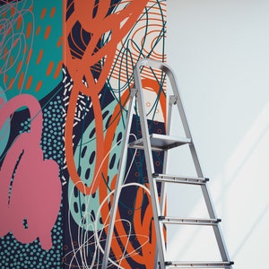 May include: A silver step ladder is positioned in front of a wall with a colorful abstract wallpaper featuring geometric shapes, lines, and dots in shades of blue, green, orange, and pink.