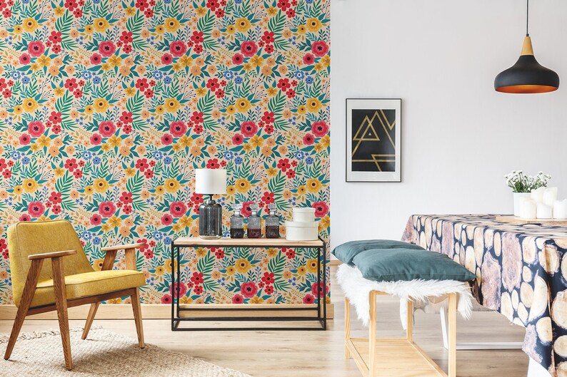 May include: A living room interior with a floral wallpaper, a yellow armchair, a side table with a lamp, and a wooden bench with a white faux fur throw and teal cushions. The room has a modern and eclectic style.