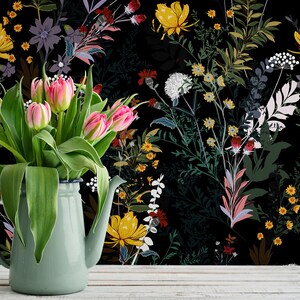 May include: A bouquet of pink tulips in a light green pitcher against a black background with a floral pattern. The flowers are arranged in a vase with a white rim.