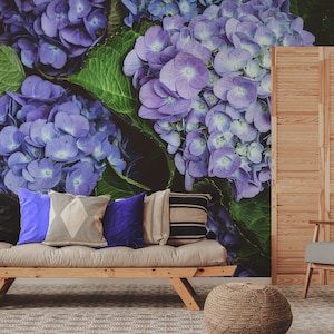 May include: A living room with a sofa and an armchair in front of a wall mural featuring a close-up of purple hydrangeas.