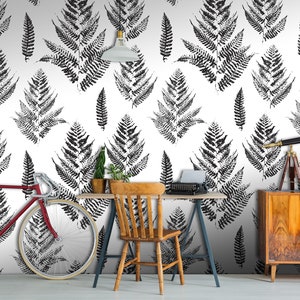 K&ouml;nnte beinhalten: Schwarz-wei&szlig;es Tapetenmuster mit Farnbl&auml;ttern in einem Heimb&uuml;ro. Im Raum befinden sich ein Fahrrad, ein Schreibtisch, ein Stuhl und ein Teleskop.