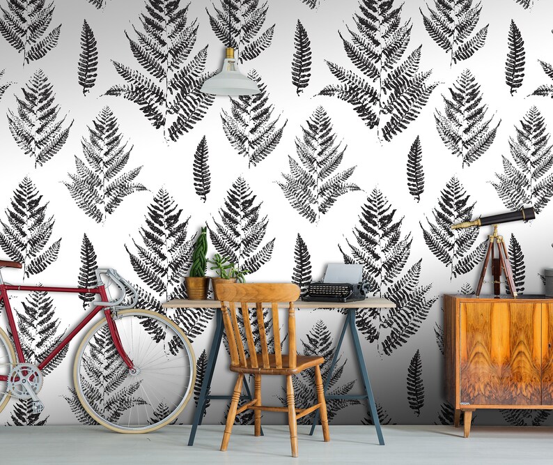 K&ouml;nnte beinhalten: Schwarz-wei&szlig;es Tapetenmuster mit Farnbl&auml;ttern in einem Heimb&uuml;ro. Im Raum befinden sich ein Fahrrad, ein Schreibtisch, ein Stuhl und ein Teleskop.
