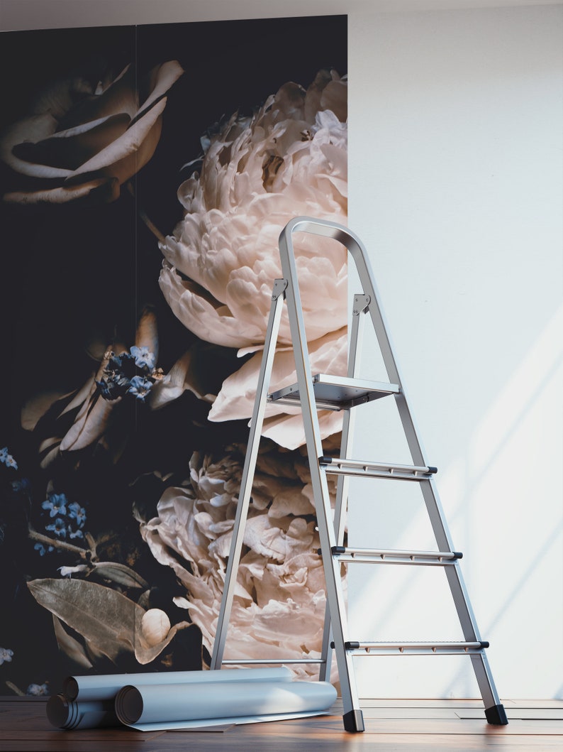 K&ouml;nnte beinhalten: Eine silberne Trittleiter mit drei Stufen steht vor einer Wand mit einer floralen Tapete mit gro&szlig;en wei&szlig;en Pfingstrosen und Rosen. Zwei Rollen Tapeten liegen auf dem Boden.