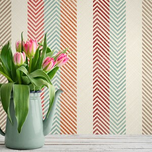 Puede incluir: Un ramo de tulipanes rosas en una jarra de esmalte azul claro sobre un fondo de rayas de chevron rojas, azules y marrones.