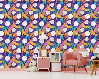 May include: A colourful wallpaper with a repeating pattern of bananas, coconuts, and dragon fruit. The wallpaper is in a room with a pink chair, a lamp, a teddy bear, and a small table with a picture frame.