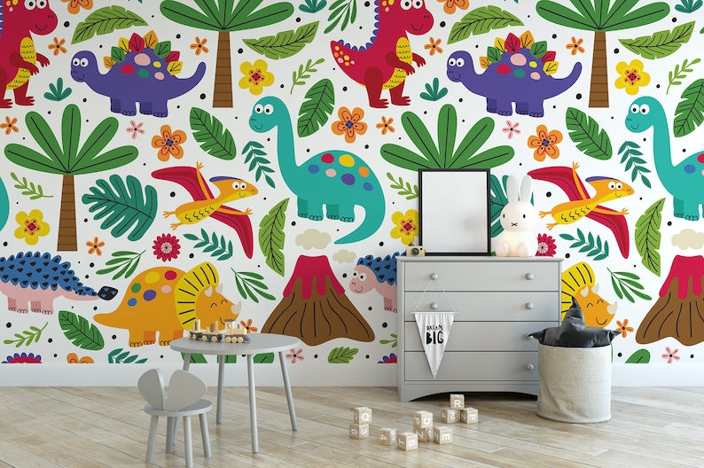 May include: A colorful dinosaur themed wallpaper mural with a variety of dinosaurs, including a triceratops, stegosaurus, pterodactyl, and a volcano. The mural is in a child's room with a small table and chairs, a dresser, and a toy basket.