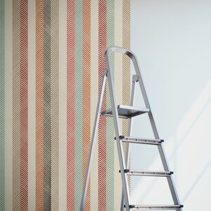 Puede incluir: Un rollo de papel tapiz con un patr&oacute;n de chevron en tonos de rojo, naranja, verde y azul se est&aacute; colocando en una pared con una escalera cerca.