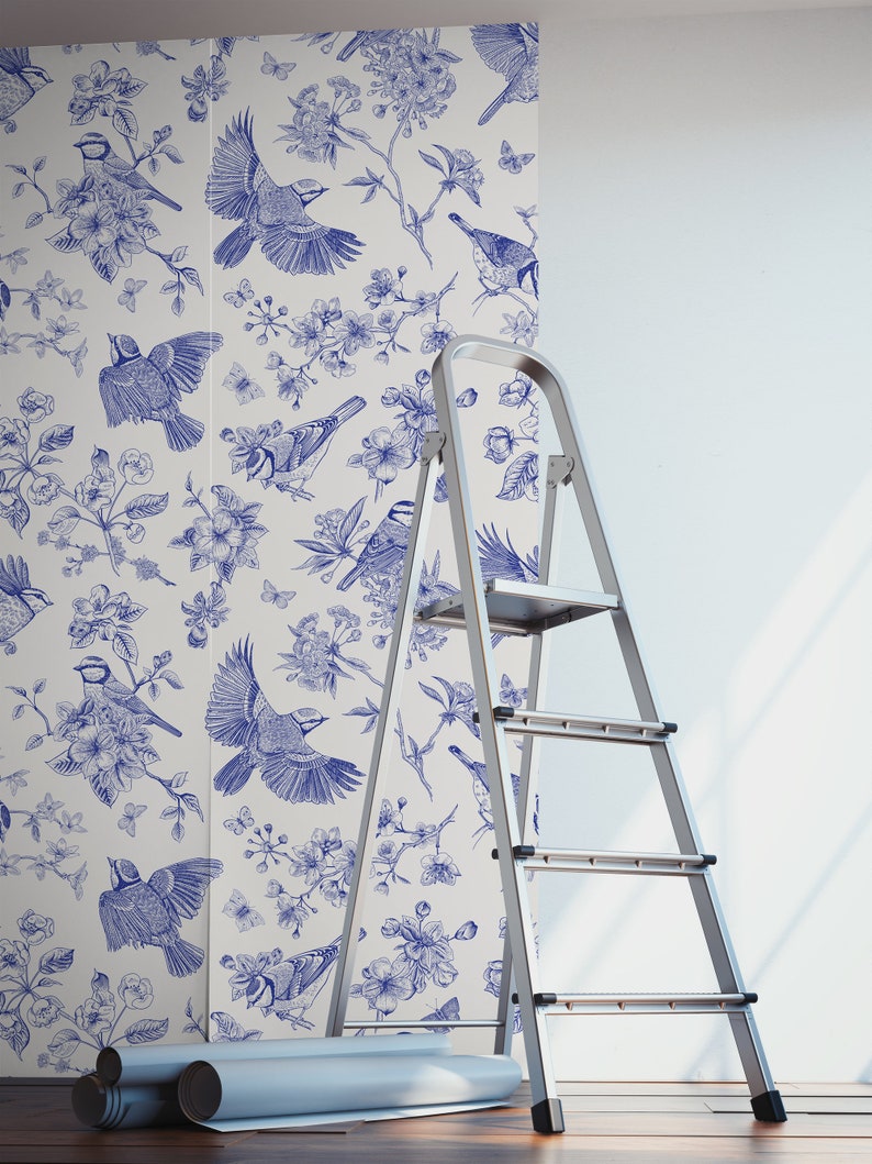 May include: A white wallpaper with a blue floral pattern featuring birds and flowers. The wallpaper is being installed on a wall with a ladder nearby.