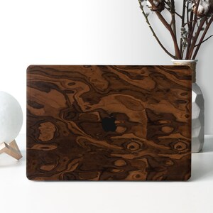 May include: A brown wood laptop skin with a dark brown wood grain pattern. The skin has a black Apple logo in the center.