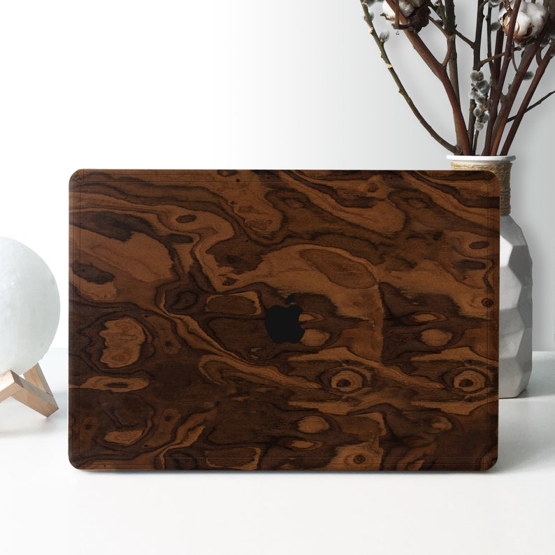 May include: A brown wood laptop skin with a dark brown wood grain pattern. The skin has a black Apple logo in the center.
