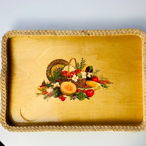 Pode incluir: Uma bandeja de servir de madeira com uma borda de vime trançada. A bandeja apresenta uma ilustração colorida de uma cesta de frutas e vegetais.
