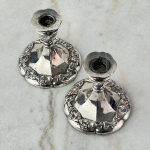 Puede incluir: Un par de candelabros de plata con un diseño de vid. Los candelabros son ornamentados y tienen un aspecto vintage.