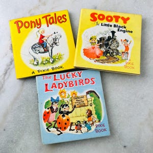 May include: Three vintage children's books with bright covers. Titles include "Pony Tales", "Sooty The Little Black Engine", and "The Lucky Ladybirds". Each is a "Pixie Book" featuring illustrations of a girl on a pony, a train, and ladybirds.
