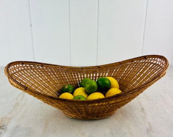 May include: A woven wicker basket in the shape of an oval with a wide, shallow bowl. The basket is filled with a mix of green limes and yellow lemons.