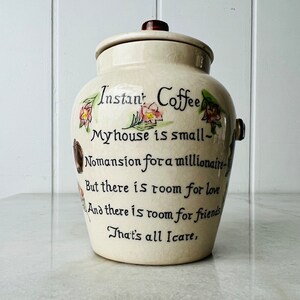K&ouml;nnte beinhalten: Wei&szlig;e Keramikdose mit Deckel, verziert mit Blumendesigns und einem handgeschriebenen Gedicht, das lautet: "Instant Coffee Myhouse is small- Nomansion for a millionaire- But there is room for love And there is room for friends That's all Icare,"
