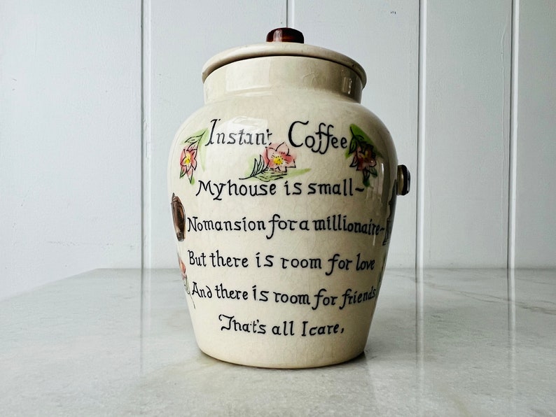 K&ouml;nnte beinhalten: Wei&szlig;e Keramikdose mit Deckel, verziert mit Blumendesigns und einem handgeschriebenen Gedicht, das lautet: "Instant Coffee Myhouse is small- Nomansion for a millionaire- But there is room for love And there is room for friends That's all Icare,"