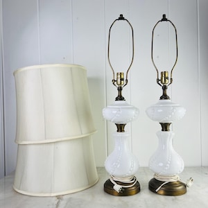 Puede incluir: Dos lámparas de mesa de vidrio blanco con diseño de cuentas y bases color latón. Las lámparas tienen una estética vintage. También hay dos pantallas de lámpara color crema, que ofrecen un juego de iluminación completo.