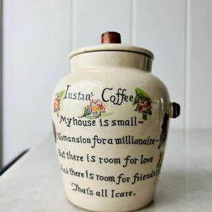 K&ouml;nnte beinhalten: Eine Kaffeedose aus Keramik mit einem Holzdeckel. Die Dose ist mit Blumen und einem handgeschriebenen Gedicht verziert, das lautet: "Instantkaffee Mein Haus ist klein - Kein Herrenhaus f&uuml;r einen Million&auml;r - Aber es gibt Platz f&uuml;r Liebe Und es gibt Platz f&uuml;r Freunde Das ist alles, was z&auml;hlt."