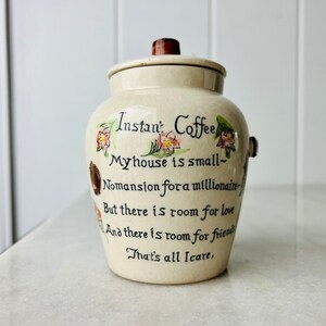 K&ouml;nnte beinhalten: Eine wei&szlig;e Keramikdose mit braunem Deckel und Blumendekor. Die Dose tr&auml;gt ein Zitat, das lautet: "Instan' Coffee My house is small- Nomansion for a millionaire- But there is room for love And there is room for friends That's all Icare."
