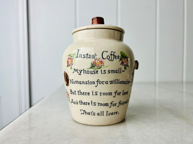 K&ouml;nnte beinhalten: Eine wei&szlig;e Keramikdose mit braunem Deckel und Blumendekor. Die Dose tr&auml;gt ein Zitat, das lautet: "Instan' Coffee My house is small- Nomansion for a millionaire- But there is room for love And there is room for friends That's all Icare."