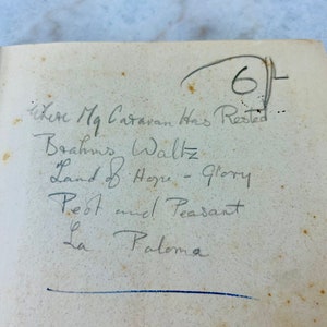 Peut inclure: Une liste de chansons manuscrites sur une page d'un livre. La liste comprend "Brahms Waltz", "Land of Hope - Glory", "Pest and Peasant", et "La Paloma".