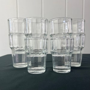 Può includere: Set di otto bicchieri di vetro trasparente con un designo testurizzato. I bicchieri sono impilati a coppie.