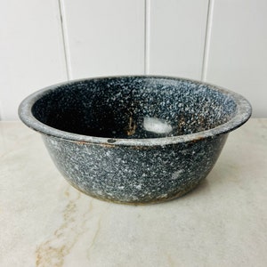 May include: A speckled grey ceramic bowl with a white speckled glaze. The bowl is round and has a slightly flared rim.
