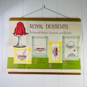 May include: A vintage poster titled "Royal Desserts" with instructions for unmolding gelatin desserts and salads. The poster features a red gelatin dessert on a pedestal, and step-by-step illustrations. The poster is held by wooden rods.