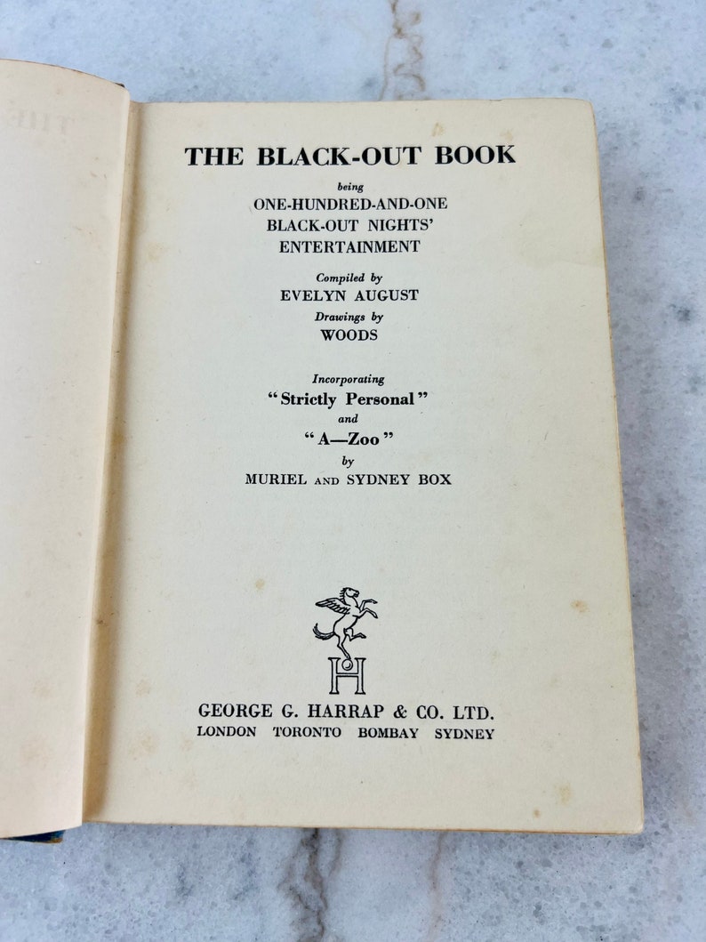 Peut inclure: La couverture d'un livre intitul&eacute; "The Black-Out Book", avec une illustration en noir et blanc d'un cheval ail&eacute; et le texte "The Black-Out Book" en gras, "being One-Hundred-and-One Black-Out Nights' Entertainment" en police normale, "Compiled by Evelyn August", "Drawings by Woods", "Incorporating "Strictly Personal" and "A-Zoo" by Muriel and Sydney Box", "George G. Harrap & Co. Ltd. London Toronto Bombay Sydney".