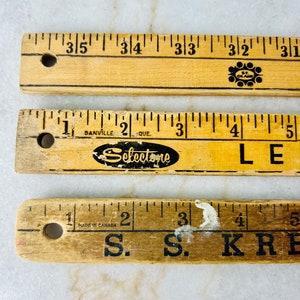 May include: Three wooden rulers with black markings. The top ruler has the text "St. Clair" and the bottom ruler has the text "S.S. KRE". The middle ruler has the text "Selectone" and "Danville, Que."