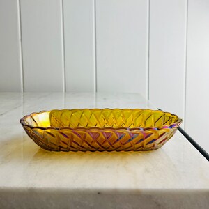 Pu&ograve; includere: Un piatto da portata in vetro ambrato vintage con un motivo a diamante. Il piatto &egrave; di forma ovale e ha un bordo leggermente ondulato.
