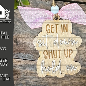 May include: A wooden sign with the text "GET IN sit down SHUT UP hold on" in white lettering. The sign is attached to a pink ribbon with white polka dots.