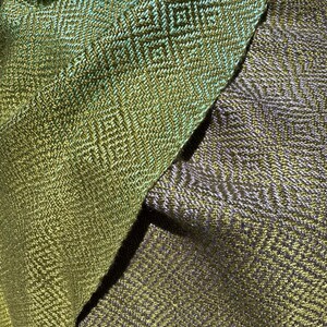 May include: Two pieces of fabric with a geometric pattern woven into the material. One piece is a green and gold colour, and the other is a purple and gold colour.