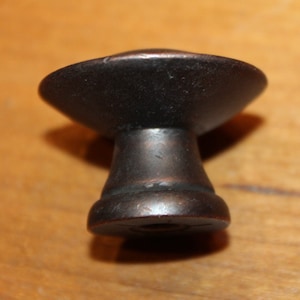 May include: A dark brown metal cabinet knob with a round top and a cylindrical base.