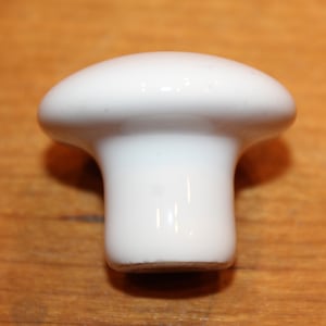 May include: White ceramic mushroom-shaped knob. The knob has a smooth, rounded top and a cylindrical base.