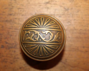May include: A brass door knob with a decorative floral design and a sunburst pattern.