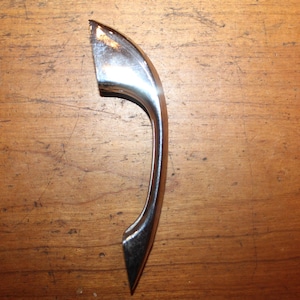May include: A silver-toned door handle with a curved design.