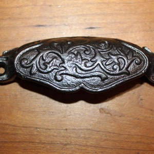 May include: Black cast iron drawer pull with a decorative floral design.