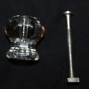May include: A clear glass cabinet knob with a faceted design and a silver screw.