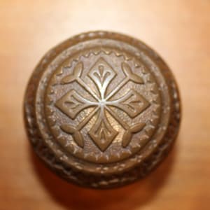 May include: A vintage brass door knob with a decorative, intricate floral design.