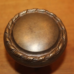 May include: A round, brass door knob with a rope-like design around the edge.