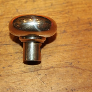 May include: A silver door knob with a round, smooth top and a cylindrical base.