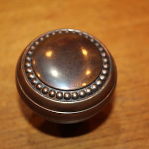 May include: A round, silver-toned cabinet knob with a beaded edge.