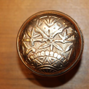 May include: A gold-toned door knob with an intricate floral design.