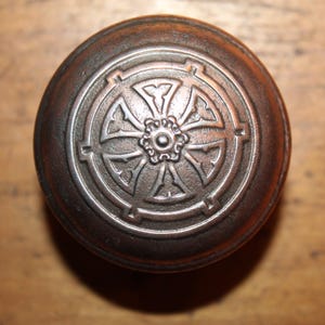 May include: A vintage-style door knob with a circular, ornate design. The knob is made of metal and has a dark brown finish.