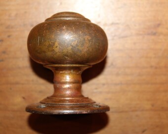May include: A vintage brass door knob with a round, domed top and a circular base. The knob has a worn, aged finish.